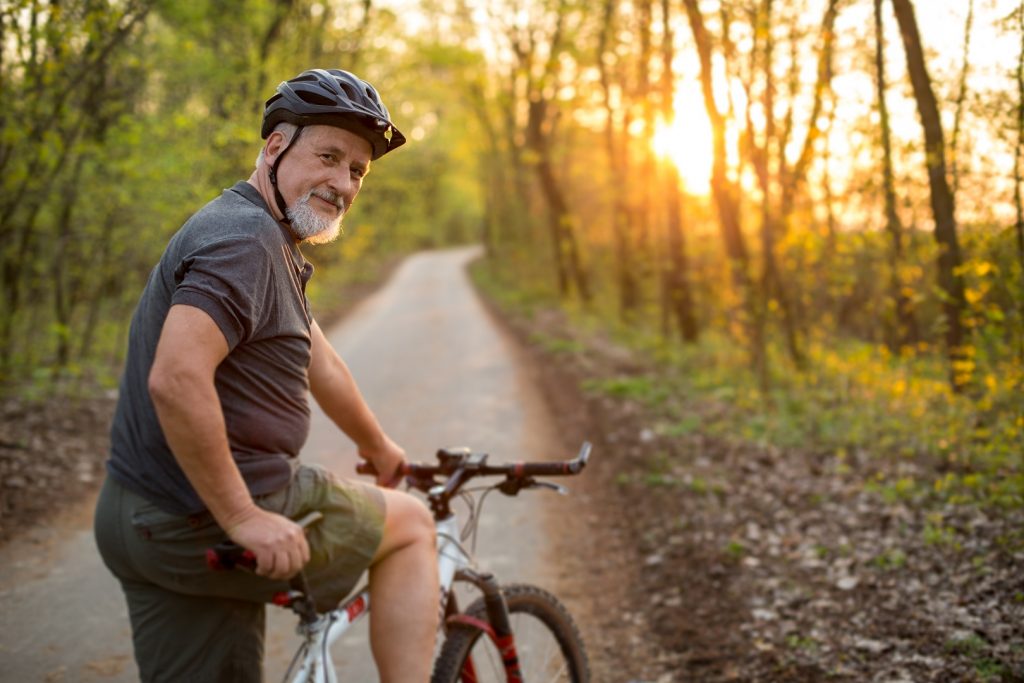 Senior man on his mountain bike outdoors Senior man on his mountain bike outdoors in forest on a lovely summer day, staying active
